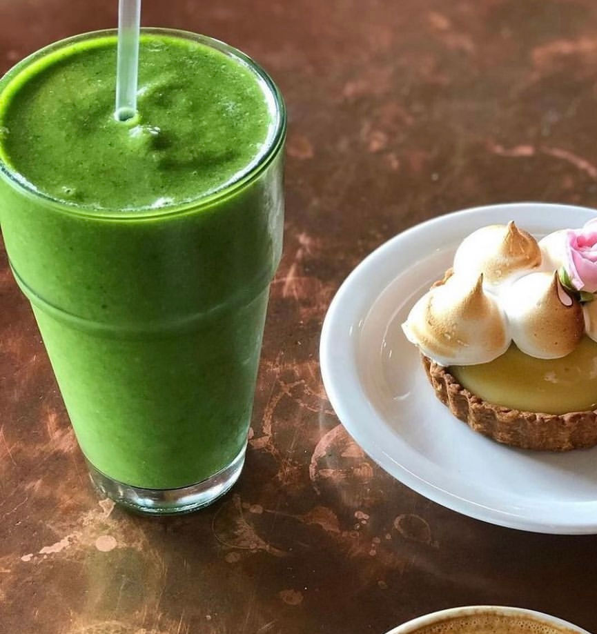 Green smoothie beside a lemon meringue tart